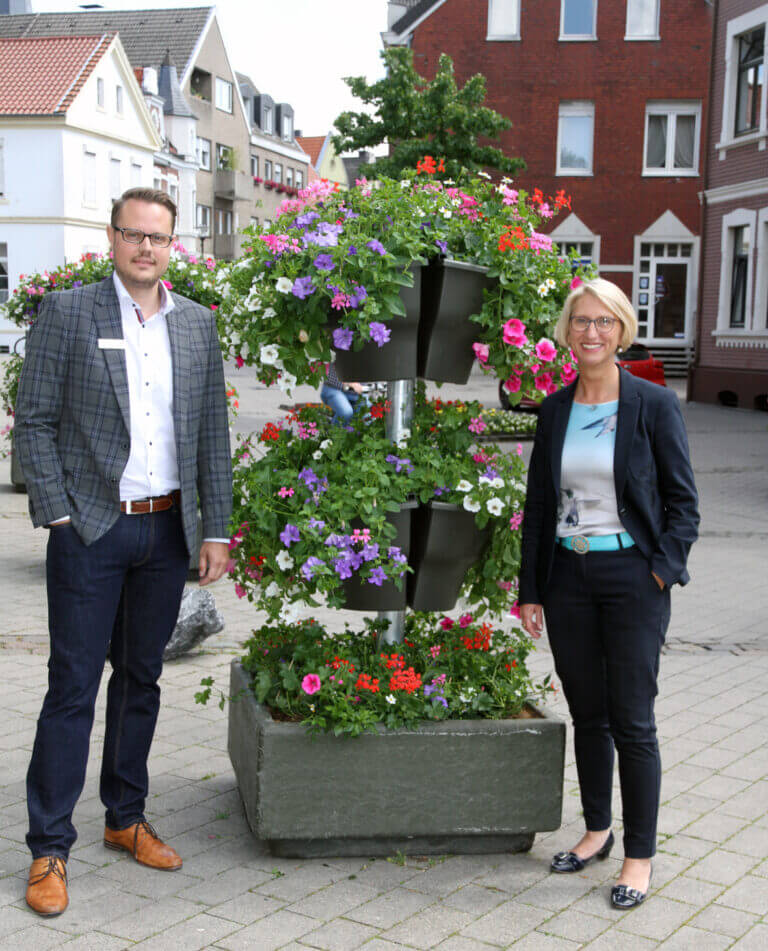 "Werne blüht auf": Carolin Brautlecht (Werne Marketing) und Andree Heimann (Sparkasse an der Lippe) präsentieren die Blumensäulen im Salinenparc. Foto: Wagner