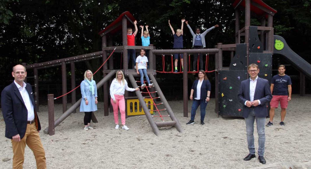 Martin Abdinghoff (links) und Bürgermeister Lothar Christ, beide als Vertreter der Sparkassenstiftung, freuen sich mit Schul- und Elternvertretern sowie Kindern über die vielen Spielgeräte auf dem Hof der Kardinal-von-Galen-Schule. Foto: Wagner