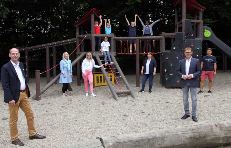 Martin Abdinghoff (links) und Bürgermeister Lothar Christ, beide als Vertreter der Sparkassenstiftung, freuen sich mit Schul- und Elternvertretern sowie Kindern über die vielen Spielgeräte auf dem Hof der Kardinal-von-Galen-Schule. Foto: Wagner