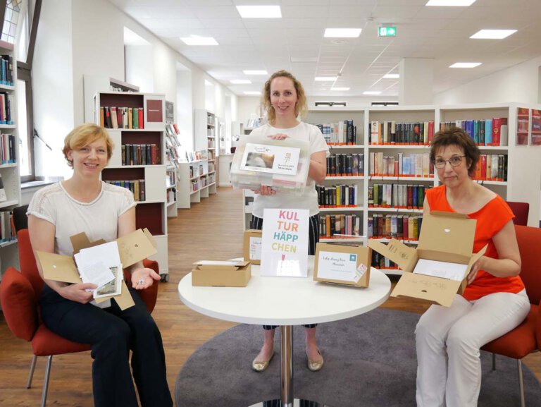 Kulturhäppchen für Genießer. Dr. Constanze Döhrer, Kathrin Kötter und Gerlinde Schürkmann (von links) präsentieren die Take-Away-Box für das „Museum zuhause“ und den fantasievollen Märchenkoffer. Foto: Gaby Brüggemann