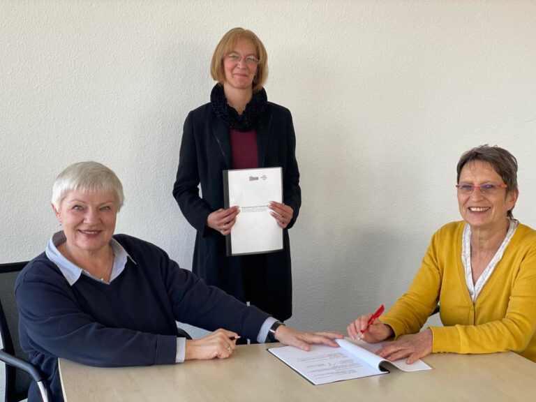 Marianne Oldenburg (l.) und Birgit Unger (r.) unterschreiben die Vereinbarung für die Zusammenarbeit im Beisein der Koordinatorin Christine Simmat (Jobcenter Kreis Unna). Foto: Jobcenter Kreis Unna/Katja Mintel