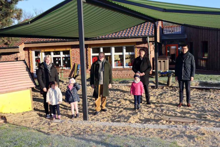 Die neue große Doppelmarkise spendet nun Schatten für den Sandspielbereich des Kindergartens St. Johannes Cappenberg. Die Leiterin Juliane Breer (v.l.), Pater Joachim Hagel, Bürgermeister Thomas Orlowski und Sparkassen-Vorstand Heiko Rautert freuen sich für die Kinder der Einrichtung über die Anschaffung. Foto: Stadt Selm / M. Woesmann