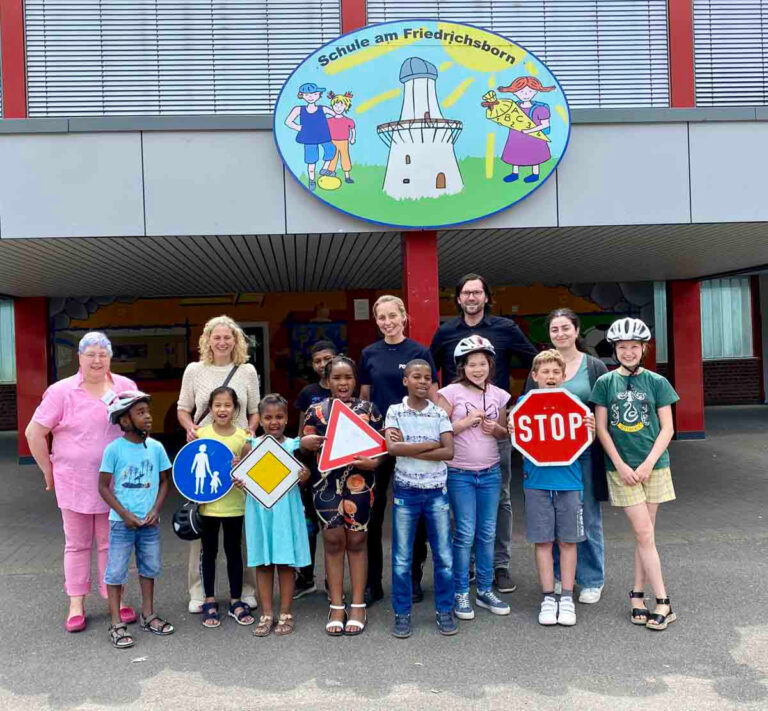 Auf dem Foto (von links): Sabine Schwalbert (Sprachlernbegleiterin), Sylke Schertel (Schulleiterin), Petra Hölscher (Polizei Unna), Jan Tarik Delkus (KI Unna), Mirhiban Uyar (Sprachlernbegleiterin) mit den einigen der teilnehmenden Kinder. Foto: Kreis Unna