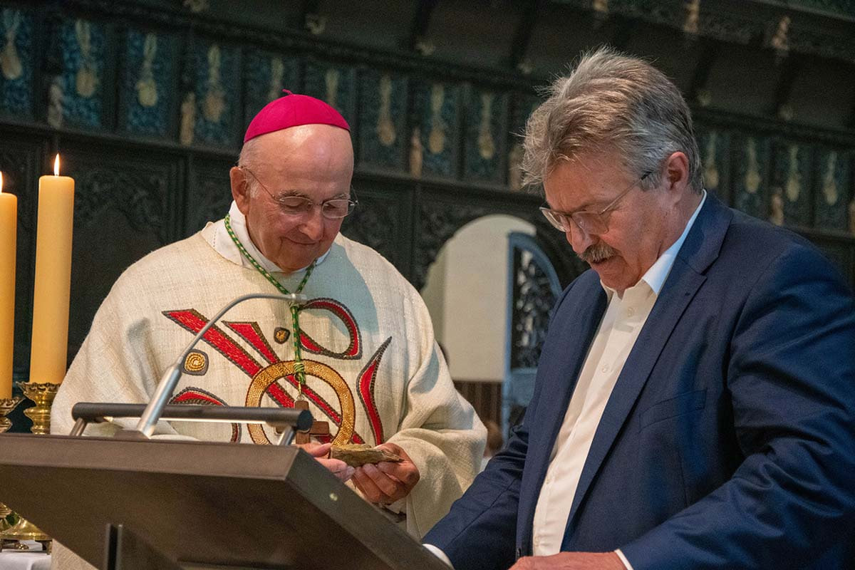 Prof. Dr. Alfons Rinschede vom Kirchenvorstand überreichte Bischof Dr. Felix Genn einen Stein der Kirche als Erinnerung. Foto: Bischöfliche Pressestelle/Michaela Kiepe