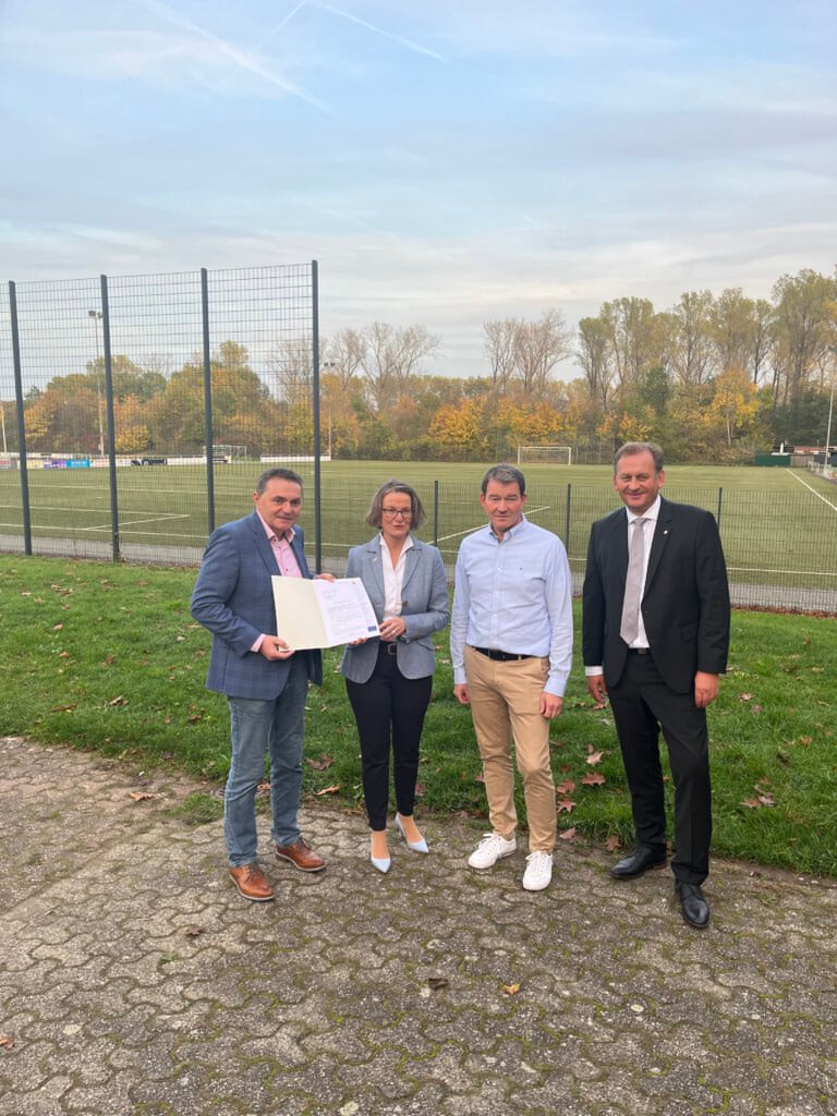Den Förderbescheid übergab Ina Scharrenbach im Beisein von Bürgermeister Dietmar Bergmann (links) und MdL Dietmar Panske (rechts) an den Vorsitzenden des FC Nordkirchen, Dietmar Koch. Foto: Gemeinde Nordkirchen