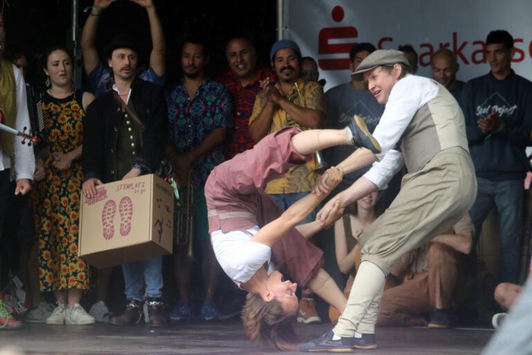 Zum Auftakt des Straßen-Festivals stellten sich die Künstler/innen auf der Sparkassenbühne vor. Die geplante Parade durch die Innenstadt fiel dem Regen zum Opfer. Foto: Wagner
