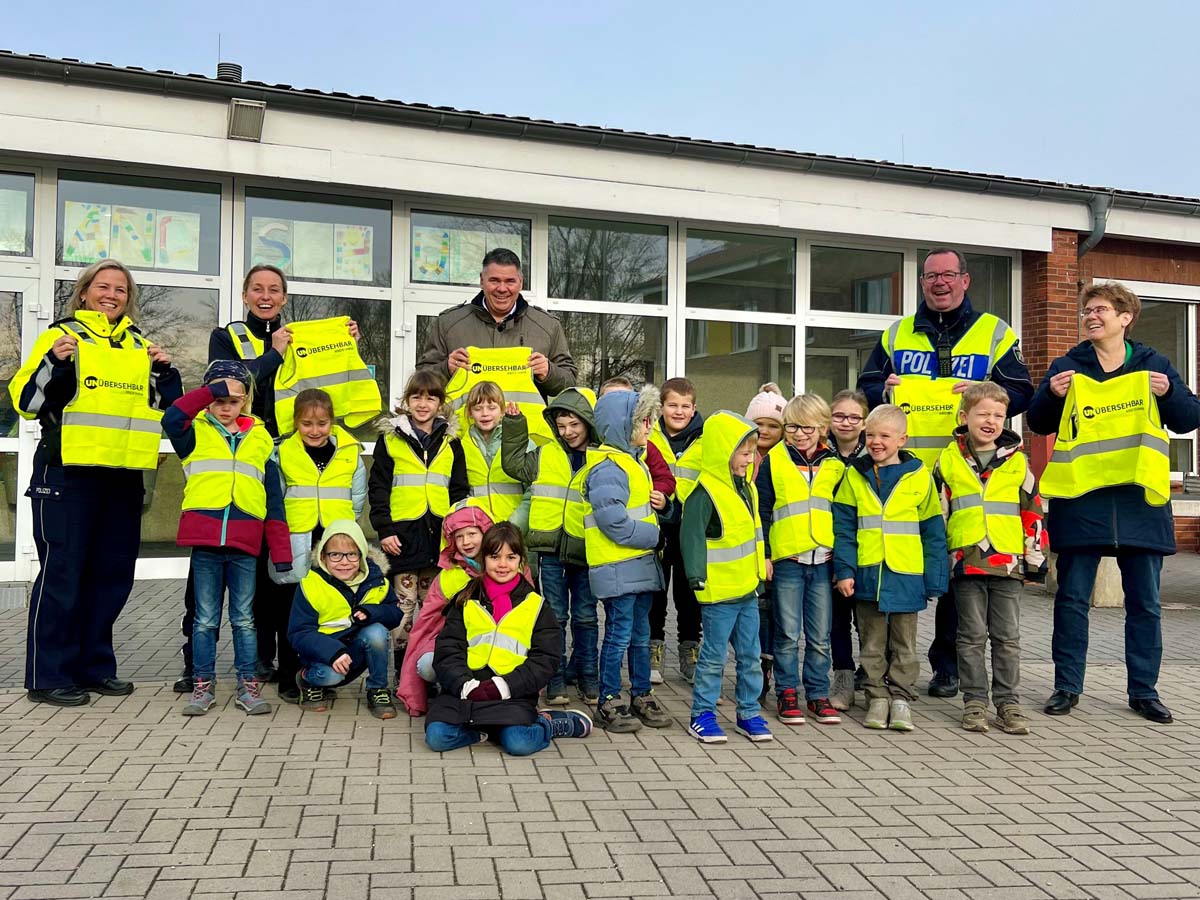 Landrat Mario Löhr und Vertreterinnen der Kreispolizeibehörde übergaben die Kinderwarnwesten an Erstklässler/innen der Uhlandschule in Werne. Foto: Polizei