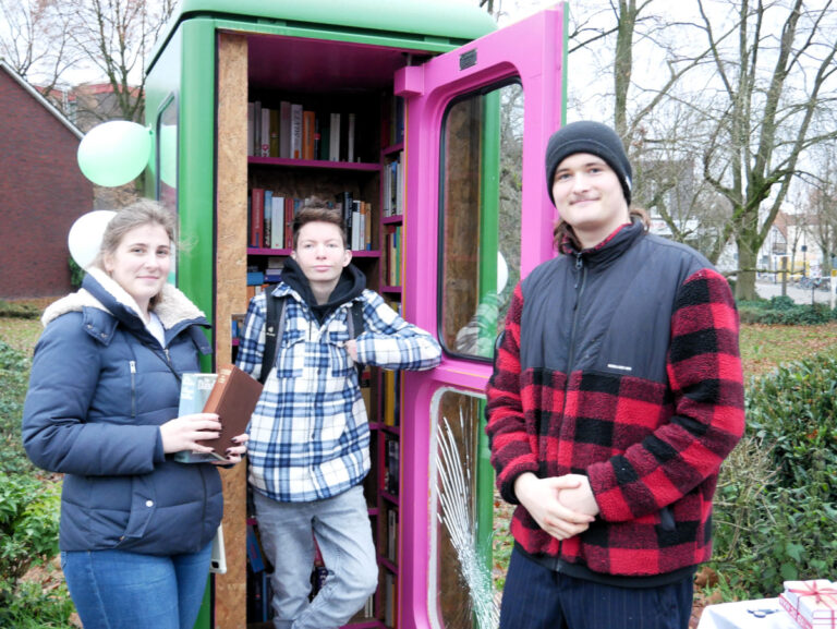 Charlotte von Loe, Kilian Hocevar und Joshua Eike (v.l.) zeigen das von Grund auf erneuerte Bücherhäuschen am Busbahnhof vor. Foto: Gaby Brüggemann