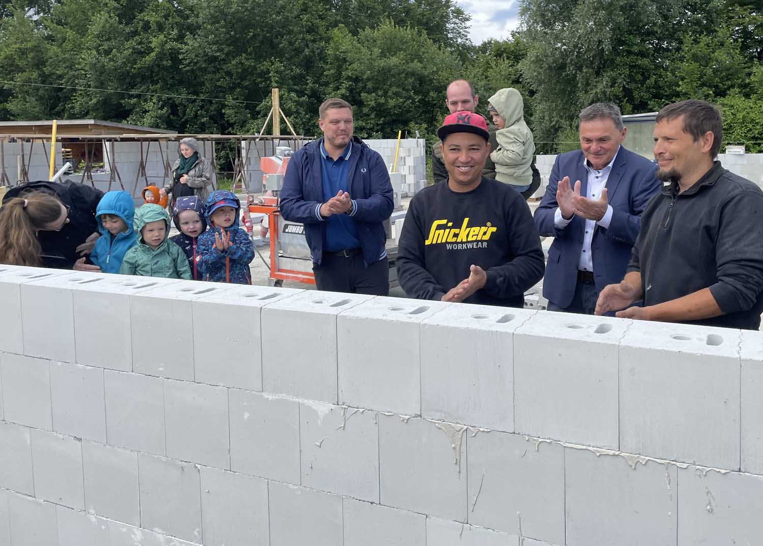 Bei der Grundsteinlegung für eine neue Kita an der Oberstraße in Südkirchen mauerte Bürgermeister Dietmar Bergmann (2.v.r.) unter den neugierigen Blicken einiger Kita-Kinder und von Axel Lorenz vom Investor Gebrüder Lorenz (M.) eine Zeitkapsel ein. Foto: Gemeinde Nordkirchen/Hauck