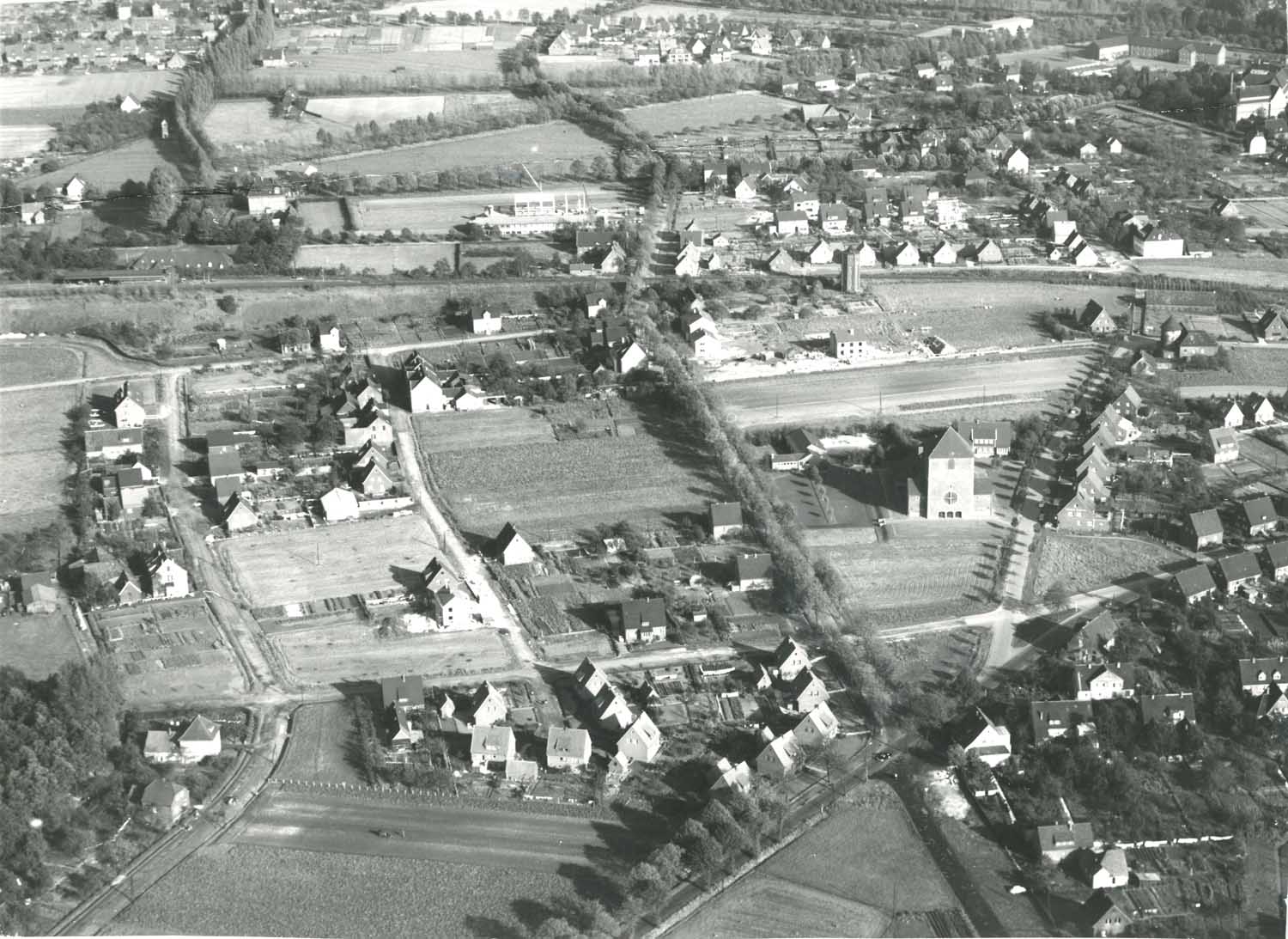 Das alte Luftbild mit Blick nach Osten stammt aus dem Jahr 1961. Es zeigt den Werner Westen mit der Pfarrkirche Maria Frieden im Mittelpunkt. Von links nach rechts kann man die Straßen Münsterfort, Haferfeld/Kolpingstraße, Ovelgönne, Windmühlenberg erkennen. Der quer verlaufende und noch nicht ausgebaute Goetheweg mündet am sogenannten „Dreieck“ in die Selmer Straße. Im Hintergrund erkennt man gut die Bahnline mit dem Werner Bahnhof und dem ehemaligen Wasserturm an der Overbergstraße. Foto: Stadtmuseum Werne
