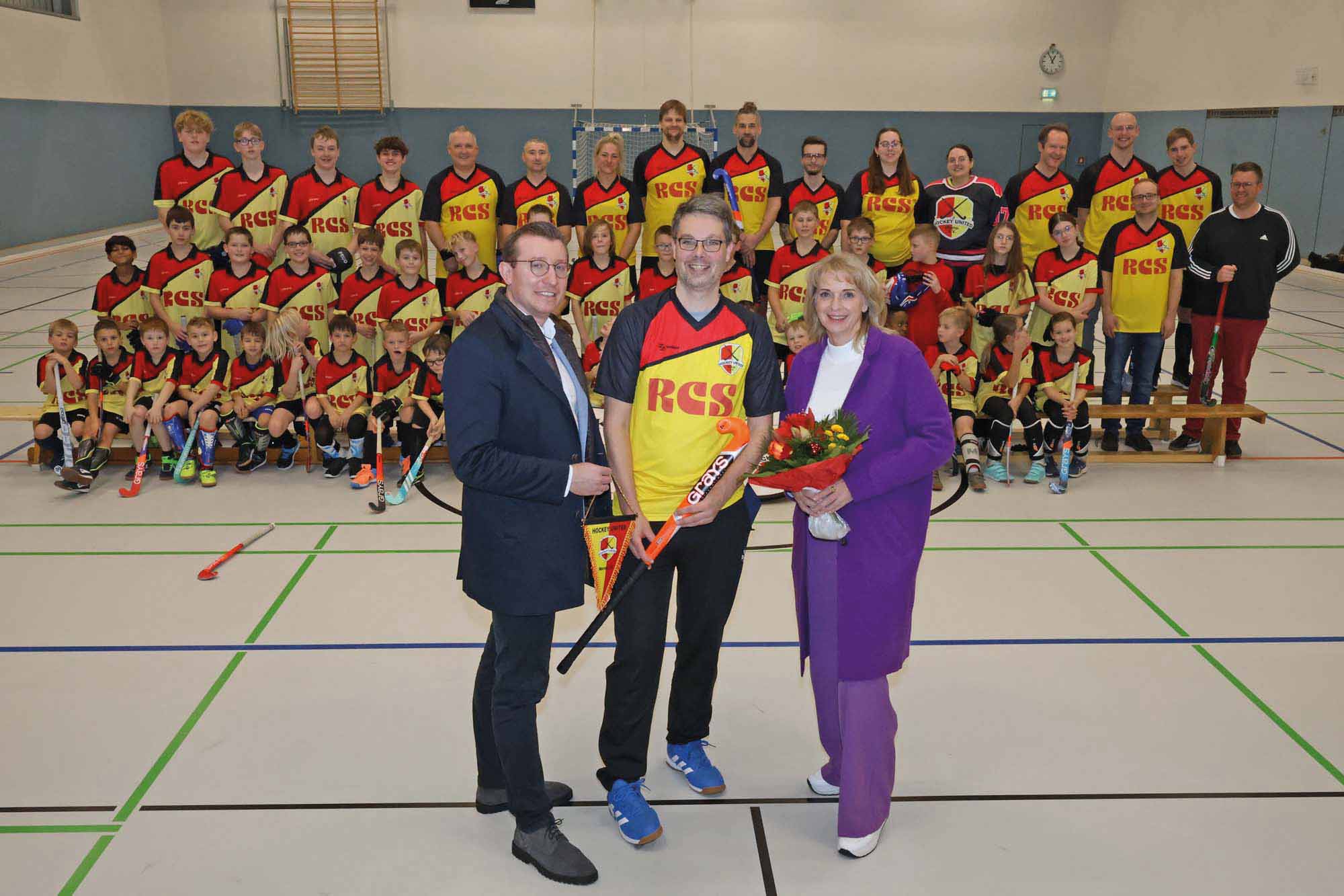 Bei der Trikotübergabe (v.l.n.r.): Alexander Rimmer, André Wagner und Adelheid Hauschopp-Francke. Im Hintergrund freuen sich viele Vereinsmitglieder in ihren neuen Trikots. Foto: Volkmer