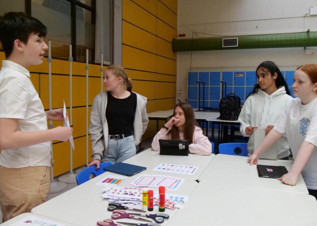 Medienscout Aaron erklärt Mitschülerinnen einen Test, mit dessen Hilfe man mehr über sein Verhalten im Internet erfahren kann. Foto: Schwarze